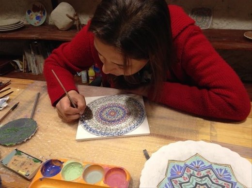 An apprentice hand painting a plate.