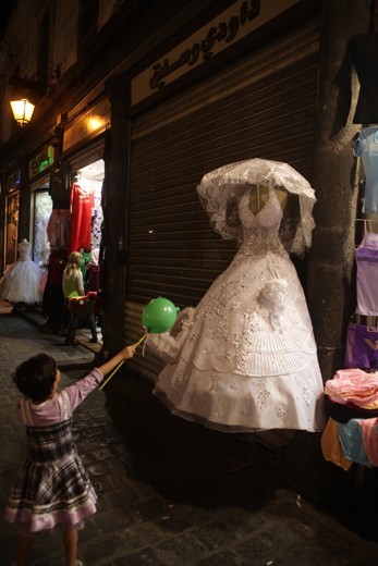 A girl looks in awe at the sight of a glittery wedding dress at Souk el Hamidiyeh