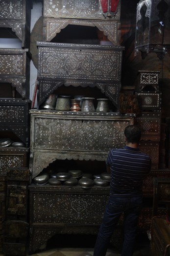 A man contemplates which mother of pearl Damascene chest will be the one