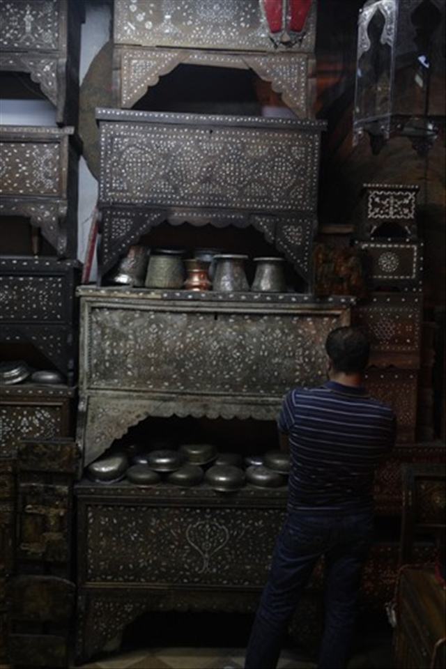 A man contemplates which mother of pearl Damascene chest will be the one