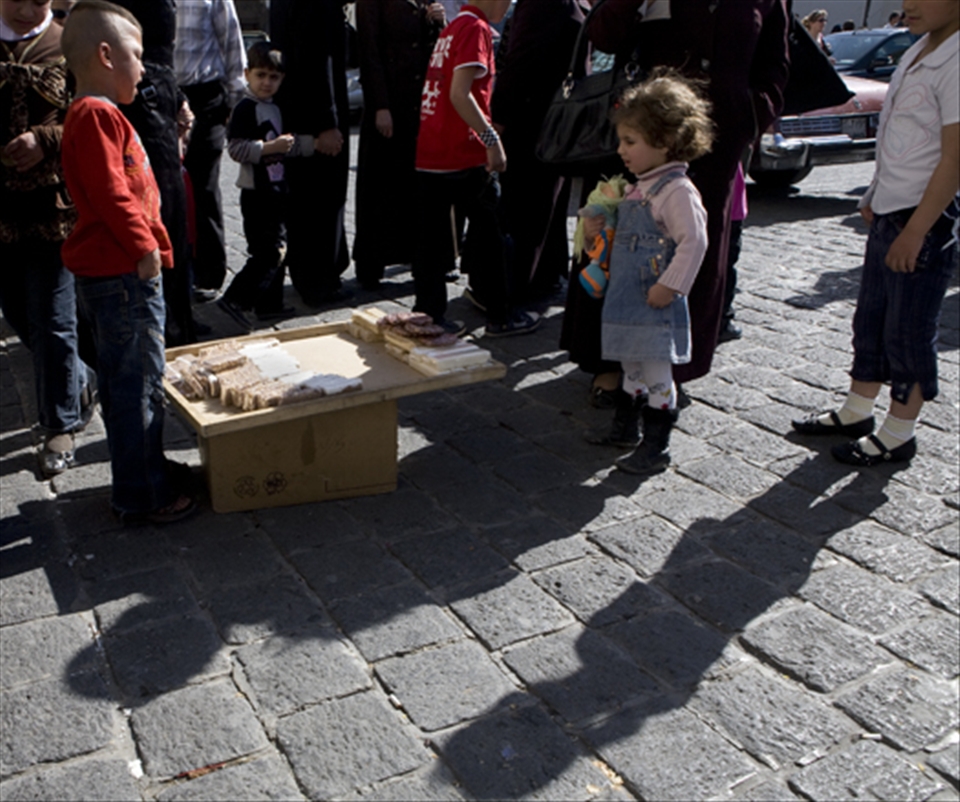 A boy selling Syrian sweets as a girl and bystanders looks on