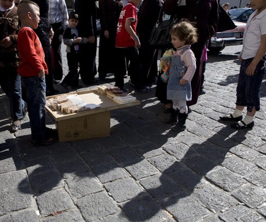 A boy selling Syrian sweets as little girls looks on