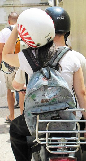 A couple cruising down the street on the classic Italian mode of transportation