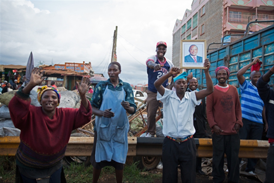 A group of Kenyans celebrate after the  Supreme Court of Kenya rules that the 2013 Presidential Elections here indeed conducted in compliance with the Constitution and were not rigged. A man (fourth from left) holds up a framed portrait of Uhuru Kenyatta, the leader of the winning party, TNA.