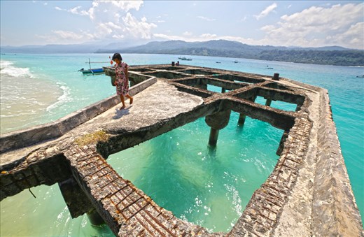 A young girl walking on a decaying wharf