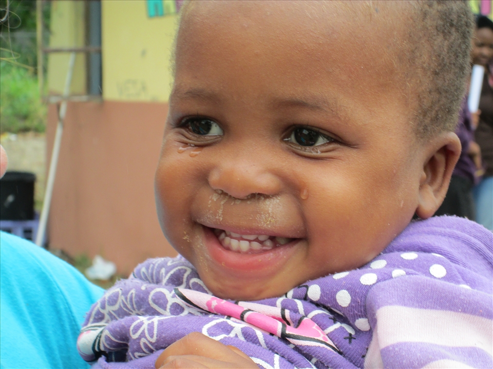 A little Zulu girl smiling through her tears.