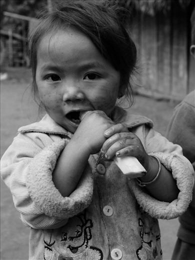 Young girl eating sugar cane, hill tribes bordering Laos