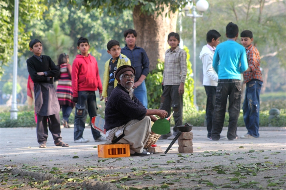 A local 'Paparwala' (traditional cracker vendor) absentmindedly fans his mini open grill while a crowd of young customers surround him