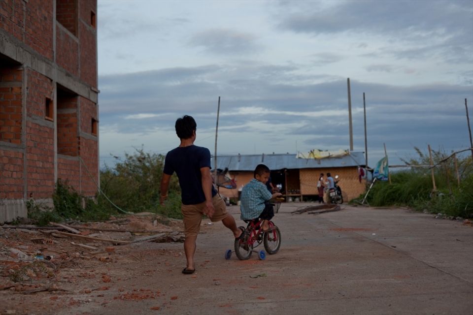 A boy and his uncle play alongside the construction site where members of his family are employed at a cheap rate, as migrant workers. (Lamphun, Thailand)