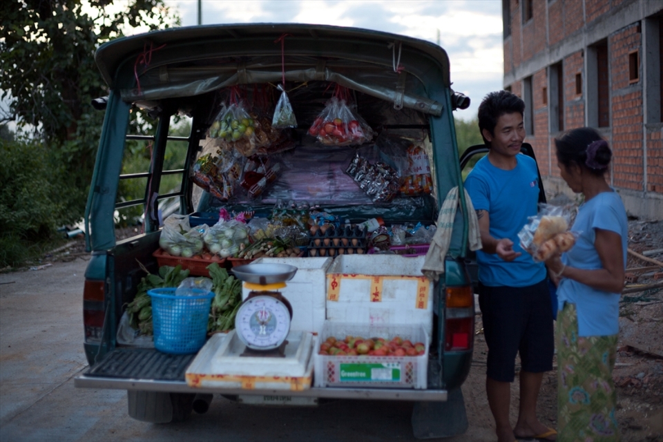 This local merchant visits the family home every evening. With little access to transportation, or money for fuel, purchasing groceries is made easier this way. (Lamphun, Thailand)