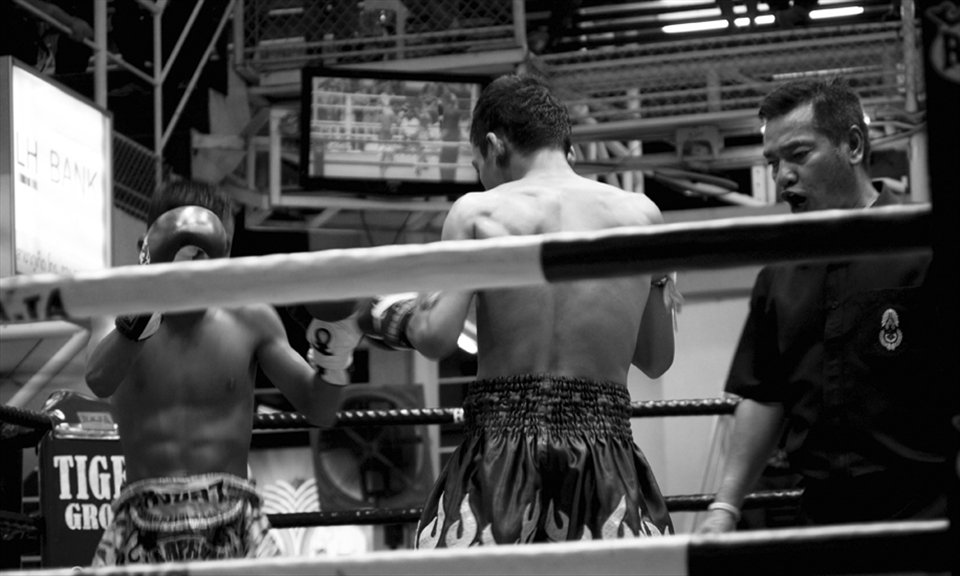 The ring is lit up with blinding fluorescence as the referee barks instructions.