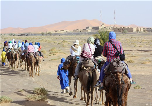 At the beginning of the journey, buildings are present on one side even as small dunes litter the other horizon. As the Berber guides direct the camels, they joke in broken Arabic with the student travelers.