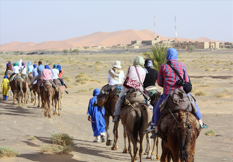 At the beginning of the journey, buildings are present on one side even as small dunes litter the other horizon. As the Berber guides direct the camels, they joke in broken Arabic with the student travelers.
