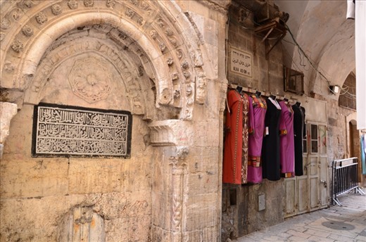 Dresses hang on the wall of a market in the centre of Jerusalems old city. The vibrant colours and patterns of the arabesque clothing nods towards modernity whilst the shape retains tradition. 