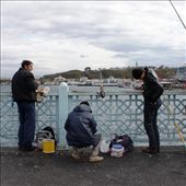 Along the Galata Bridge dozens of men line their fishing rods with buckets at their feet while vendors shout for business: by sarahg, Views[145]
