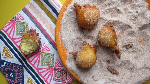 Rolling the doughnuts in cinnamon sugar.