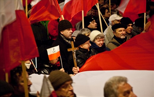 Within Polish nationalism rests strong Catholic belief, here shown by the crucifix held at the end of a long Polish flag. The symbol on the neighbouring flag stands for ‘Powstanie Warszawskie’ or ‘Warsaw Uprising’. In 1944 the citizens of Warsaw rose up to fight against their Nazi occupiers and so this symbol represents the pride Poland has for keeping their nation independent.