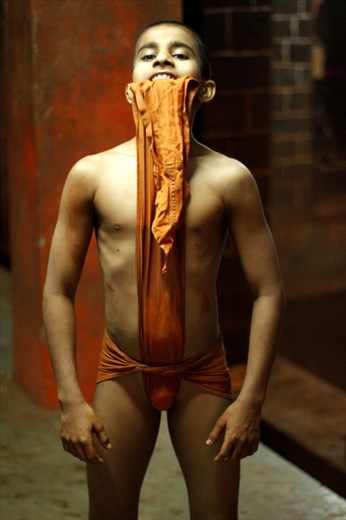 LANGOT The langot is the traditional costume of Kushti. The 'saffron' colour of langot signifies ‘sacrifice’. It is a small piece of cloth used to cover human genitals. It allows flexibility and increases the degrees of freedom of a wrestler. Also it allows maximum possible contact of one’s body with the specially prepared soil, which is known for its anti-septic properties. Now a days, Mats and Nylon made sports costumes are also coming into picture along with Soil pit and langots. 
  