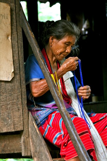 This elderly woman sits in a small hut in the hills of a local Chang Mai village making traditional hill-tribe crafts and jewelry to sell to tourists. 