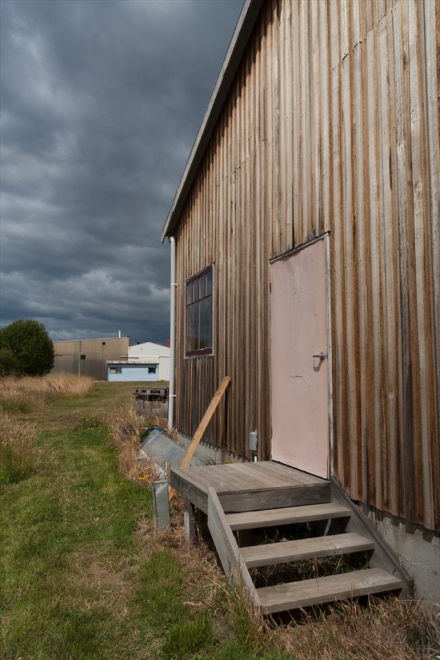 On the banks of the quiet Huon River a weathered boat shed stands proud in the face of a building storm.