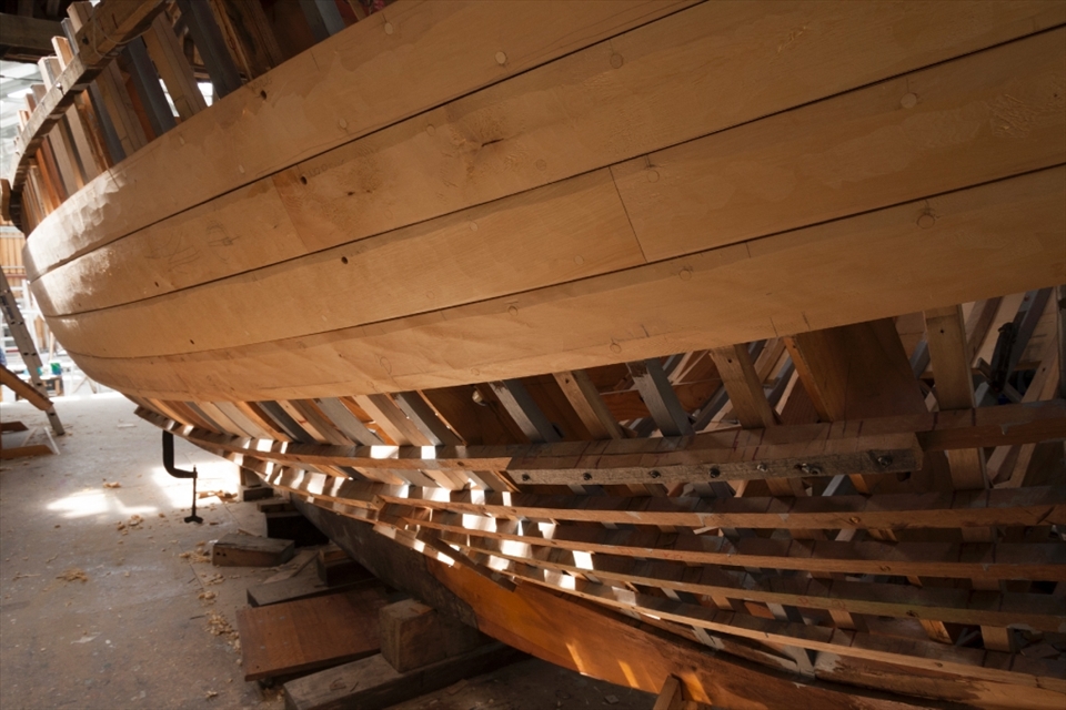 “Peggy” a 22ft Yacht designed and built by Adrian Dean and named after his wife. At its current state, Huon Pine planks begin to enclose the skeleton of the hull as light leaks through the uncovered areas.