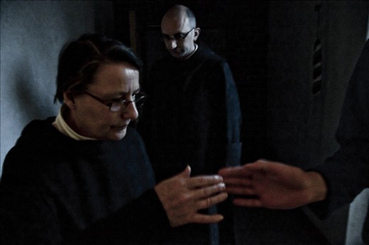 Holy water is passed from hand to hand as the monks proceed into the oratory