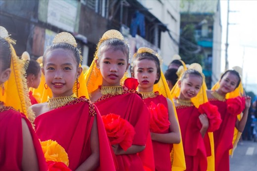 Girls walk along an avenue in Cebu city dressed in traditional Sinulog costumes.