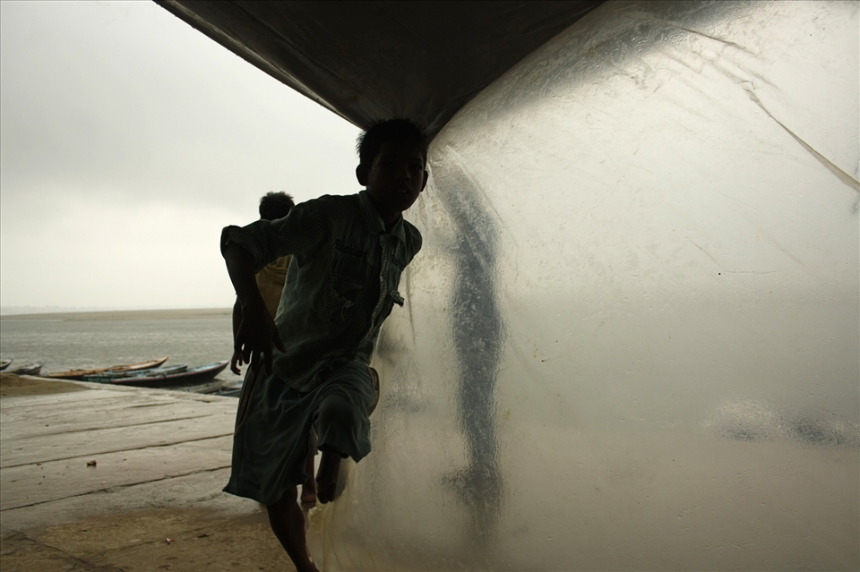 The kids of fishermen leave their play to take shelter. Distant boats wait.