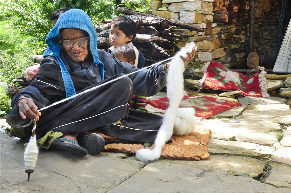 Tradition Savior woman in traditional attire spinning wool with spindle. 