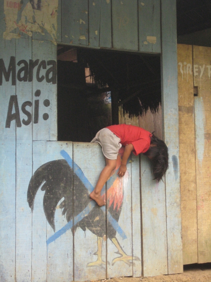 Hanging around :)

This photo was taken in a small village in Iquitos, Loreto. The people mark their houses in times of political elections. It was Saturday morning and this little girl was hanging around on the outside of her window.