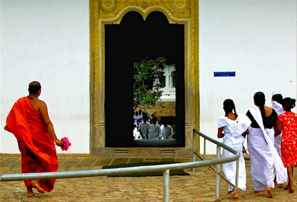 A monk and a group of girls converge on a doorway to the cave temple in Dambulla.
