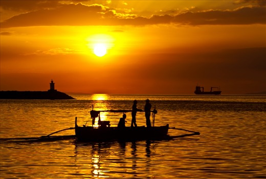 Fishermen head out to sea as the sun stes over Manila Bay