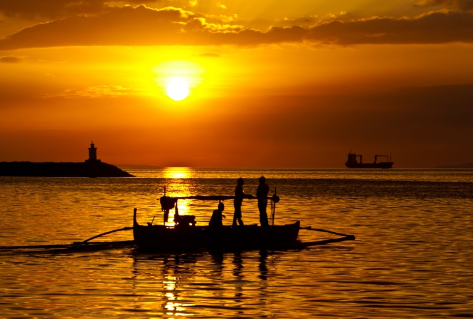 Fishermen head out to sea as the sun stes over Manila Bay