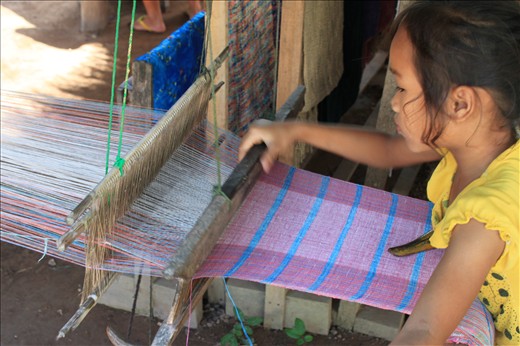A different life from early on. Weaving while mum sells to tourists.