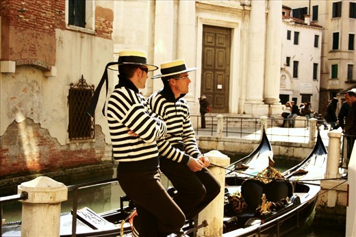 Venice is home to the picture-esque canals, romantic gondolas, and colorful buildings.  Here two gondoliers tie up their gondolas to take a break from the crowds and relax.