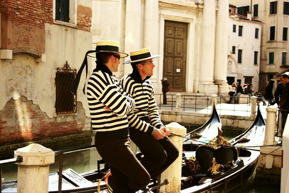 Venice is home to the picture-esque canals, romantic gondolas, and colorful buildings.  Here two gondoliers tie up their gondolas to take a break from the crowds and relax.