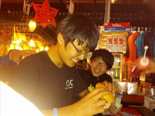 Boys enjoying(?) a burger at the Siem Reap night market