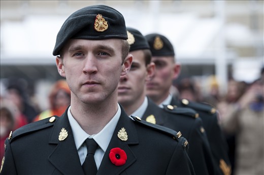 The cold chill bites exposed flesh and the soldiers stand alert, reflecting on their own journey to serve and protect our nation.  It is an impressive crowd of dedicated on-lookers braving the November frost-laden air to take in “a moment of silence” to honour all soldiers of war. The heavy silence lays like a cold blanket, cascading over the thousands present.  Only the reverence of the moment is a warm embrace holding the chill at bay. The eyes of the soldier penetrate right through the crowd, as his intense gaze reveals the deep sadness and emotion that lurks in his eyes.