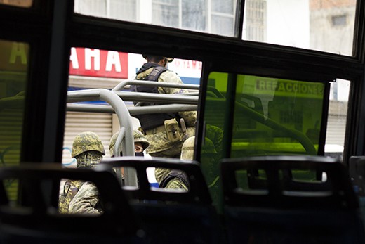 Soldiers, viewed from the bus, guard a drug-war-torn country. It's rare to find a photograph of them in action. They are ruthless, and many claim they are also corrupt.