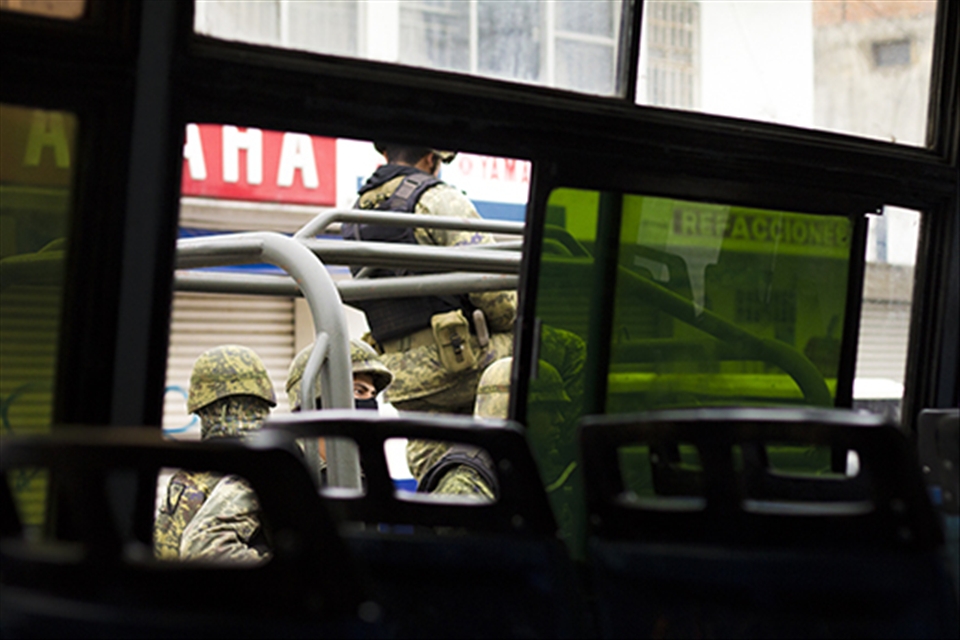 Soldiers, viewed from the bus, guard a drug-war-torn country. It's rare to find a photograph of them in action. They are ruthless, and many claim they are also corrupt.
