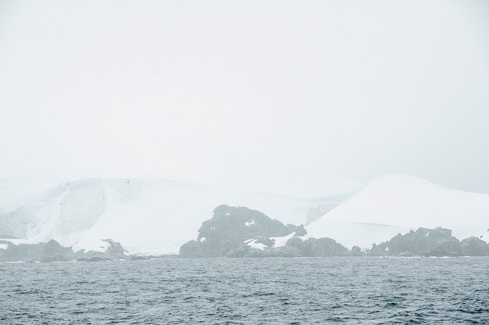 IN TO THE WILDERNESS WE GO - 

Out of the gloom of the fog, looms The Last Great Wilderness as our first sighting on the Antarctic voyage. Comprised of jagged, unforgiving rocks capped off with layer upon layer of thick snow, the Ice Continent presents a harsh environment with raging dry winds with alarming, bone chilling temperatures. A 48 hour journey on the brutal, raging seas of The Drake Passage finally brings us to calm, pristine waters of the Antarctic. 