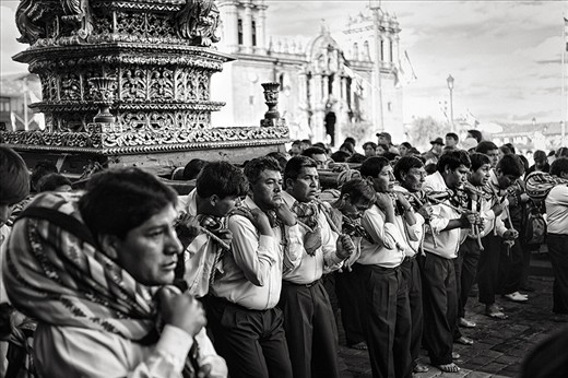 A group of men struggle under the weight of a saints' effigy as they carry it through the streets of Cusco and around the Plaza de Armas, during the festival of Corpus Christi.  They will do this all day and into the night when they will store the effegies until morning in La Catedral, a Spanish colonial cathedral, which you can see behind them.  Celebrated exactly nine weeks after Easter, it is a ritual co-opted by the Spanish in the 16th Century to Catholicize the Incan people.  The effigies are treated as living beings in a similar way as the Inca paraded their ancestors' mummies around that same plaza centuries before.