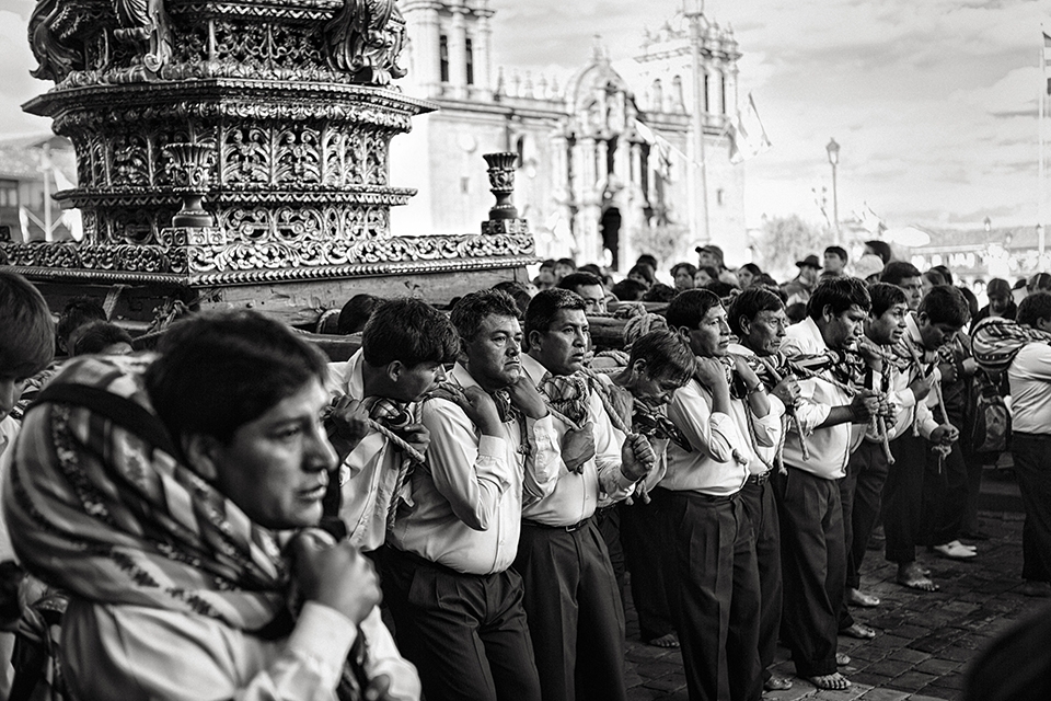 A group of men struggle under the weight of a saints' effigy as they carry it through the streets of Cusco and around the Plaza de Armas, during the festival of Corpus Christi.  They will do this all day and into the night when they will store the effegies until morning in La Catedral, a Spanish colonial cathedral, which you can see behind them.  Celebrated exactly nine weeks after Easter, it is a ritual co-opted by the Spanish in the 16th Century to Catholicize the Incan people.  The effigies are treated as living beings in a similar way as the Inca paraded their ancestors' mummies around that same plaza centuries before.