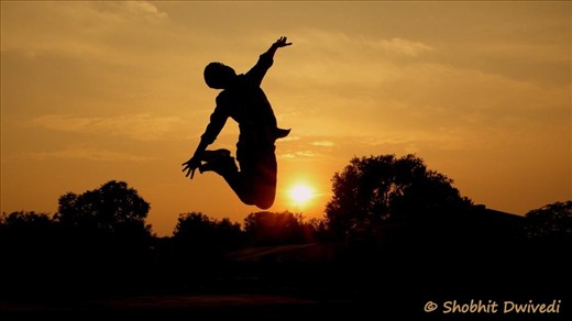 Boy is jumping durong the sunset.