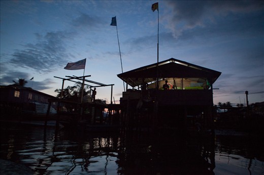 Onlookers wind down as night falls upon a ‘built on stilts’ fishing village. Sandakan - Borneo, Malaysia.  