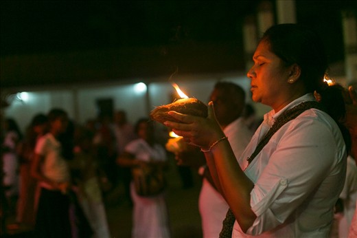 Kataragama, one of the most sacred sites in Sri Lanka. One of many devotees requests a boon from the god, holding aloft a coconut on which a camphor fire burns.
She will later smash the coconut on a rock, and hope it splits auspiciously into two equal halves.