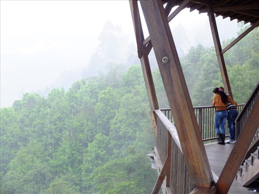 A young couple peer into the vast valleys below El Mirador (The Lookout Point) on the outskirts of Salento. Torrential rain falls as yet another massive cloud formation engulfs the entire region. The atmosphere is heavy here, both in a climatic sense and in the mood it creates.                         
