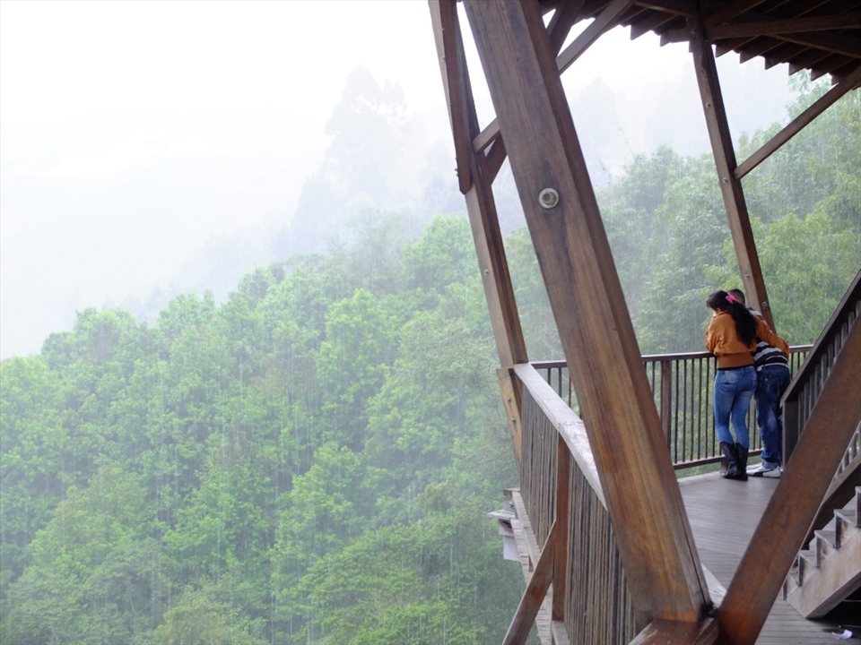 A young couple peer into the vast valleys below El Mirador (The Lookout Point) on the outskirts of Salento. Torrential rain falls as yet another massive cloud formation engulfs the entire region. The atmosphere is heavy here, both in a climatic sense and in the mood it creates.                         