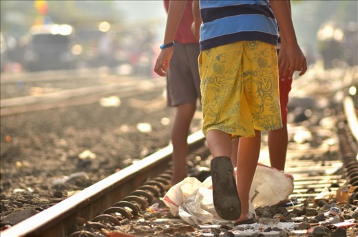 three children walking on the middle of rail,without scare the trains will pass.