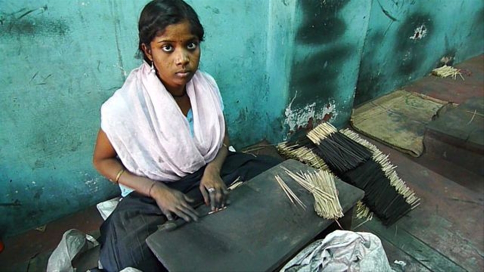 A young woman in Mysore, India, works in an incense factory to make agarbatti. She rolls bamboo sticks with charcoal powder and adhesive. The sticks are then sun-dried before they are dipped into aromatic liquids. The Mysore incense will eventually make its way into homes, offices and temples all over the world.